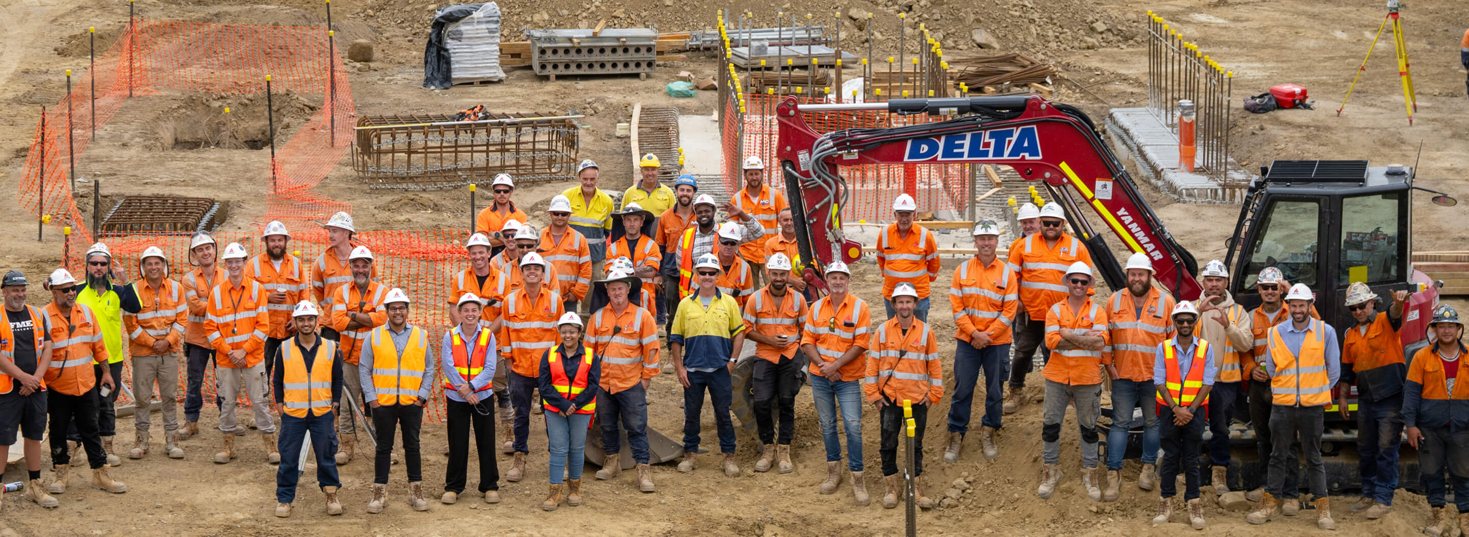 A group of construction workers poses with machinery in an industrial site, showcasing teamwork and collaboration.